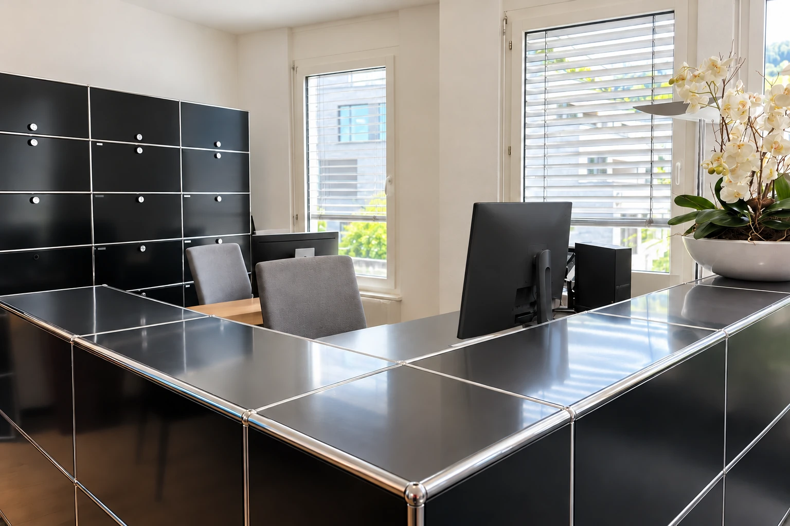 Bright PrimeDesk reception with a black counter, large windows and white orchids